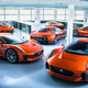 A photo of six orange Jaguar supercars parked in a warehouse.